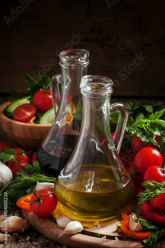 Fresh olive oil in glass carafe with tomatoes, peppers, cucumber