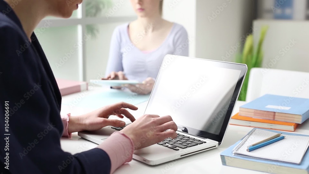 Young girls sitting at desk, studying and using a laptop, communication and learning concept, hands close up, seamless loop