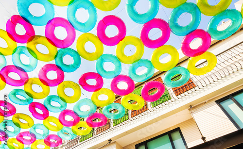 Street decoration with colorful swimming rings hanging against t