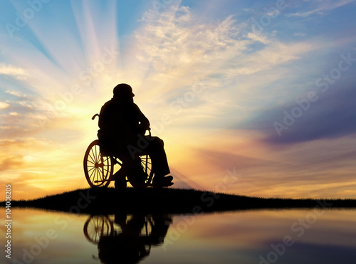 Silhouette of disabled person in a wheelchai photo