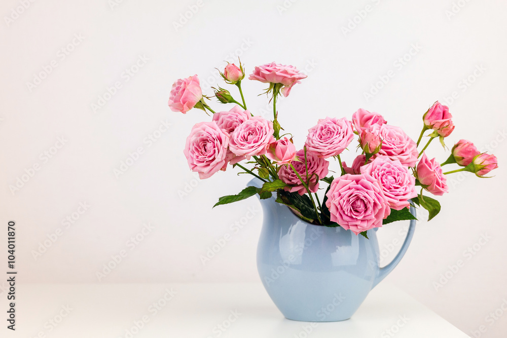 Pink flowers in blue jug. Roses in jug. Pink flowers in blue jug. Roses in jug.