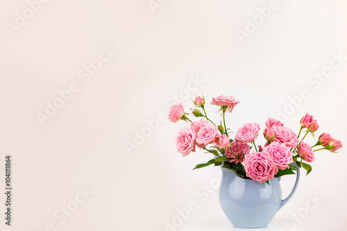 Pink flowers in blue jug. Roses in jug.