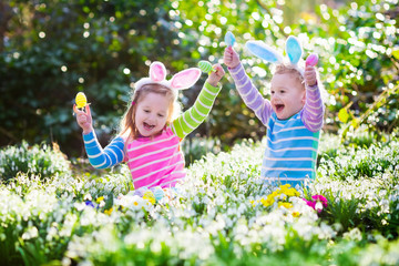 Kids on Easter egg hunt in blooming spring garden
