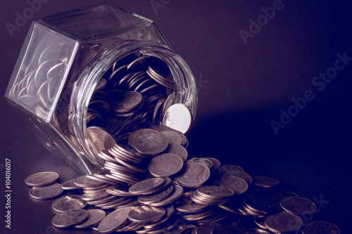 Coins spilling out of a glass bottle with filter effect retro vi
