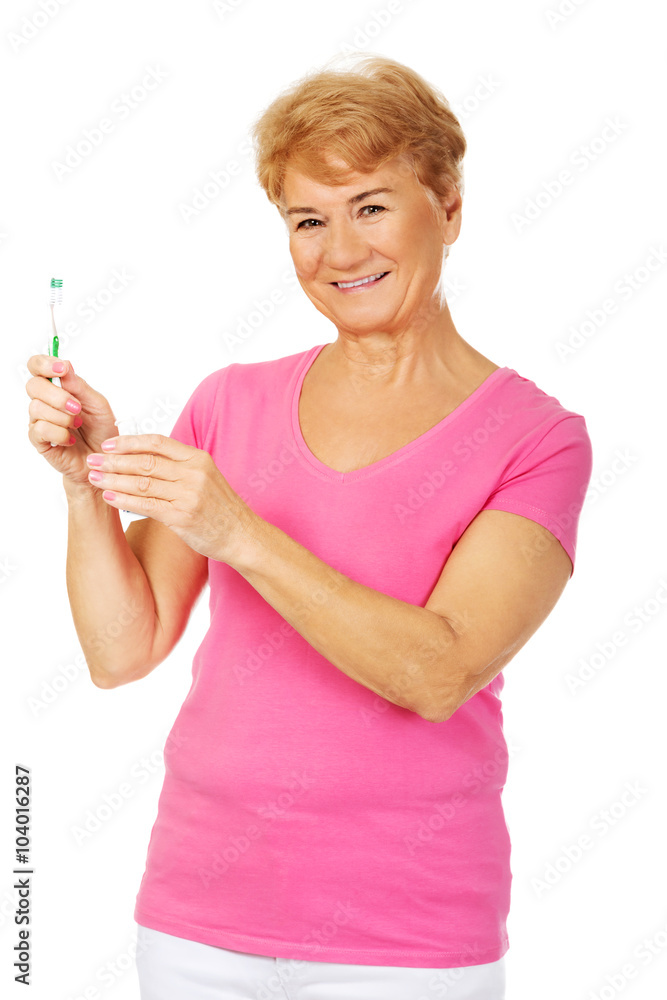Smiling senior woman holding toothpaste and toothbrush Smiling senior woman holding toothpaste and toothbrush