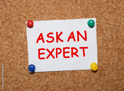 The phrase Ask An Expert typed on a white piece of note paper and pinned to a cork notice board