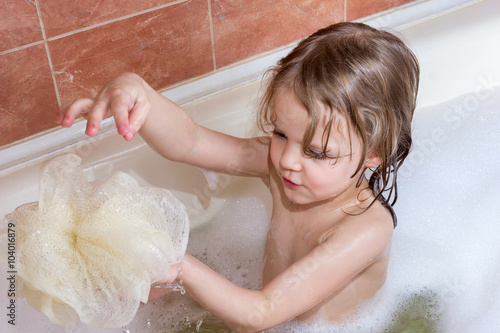 little girl taking bath with foam