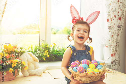 Easter. happy child girl with bunny ears and colorful eggs sitti