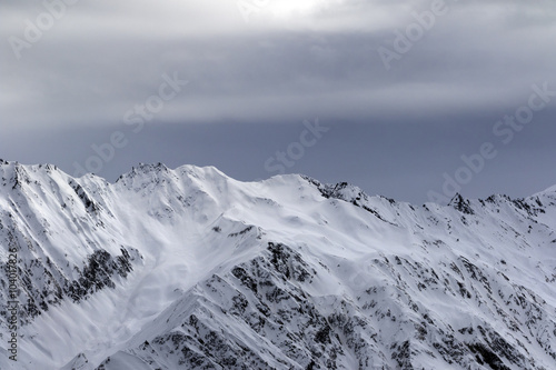 High snowy mountains and sunlight storm sky before blizzard