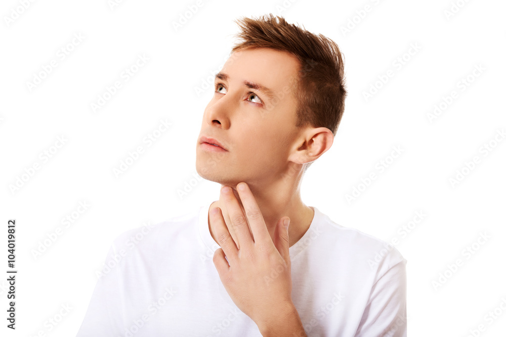 Young thinking man looks up with hand near face Young thinking man looks up with hand near face