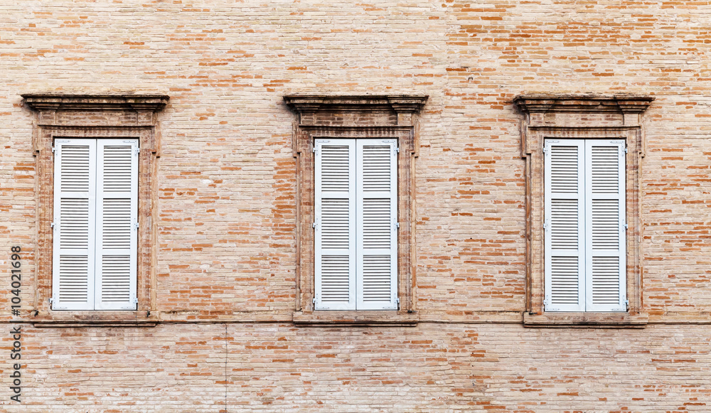 Three windows with white closed wooden shutters