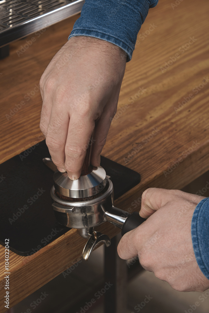 Barista using tamper to press ground coffee into portafilter Barista using tamper to press ground coffee into portafilter