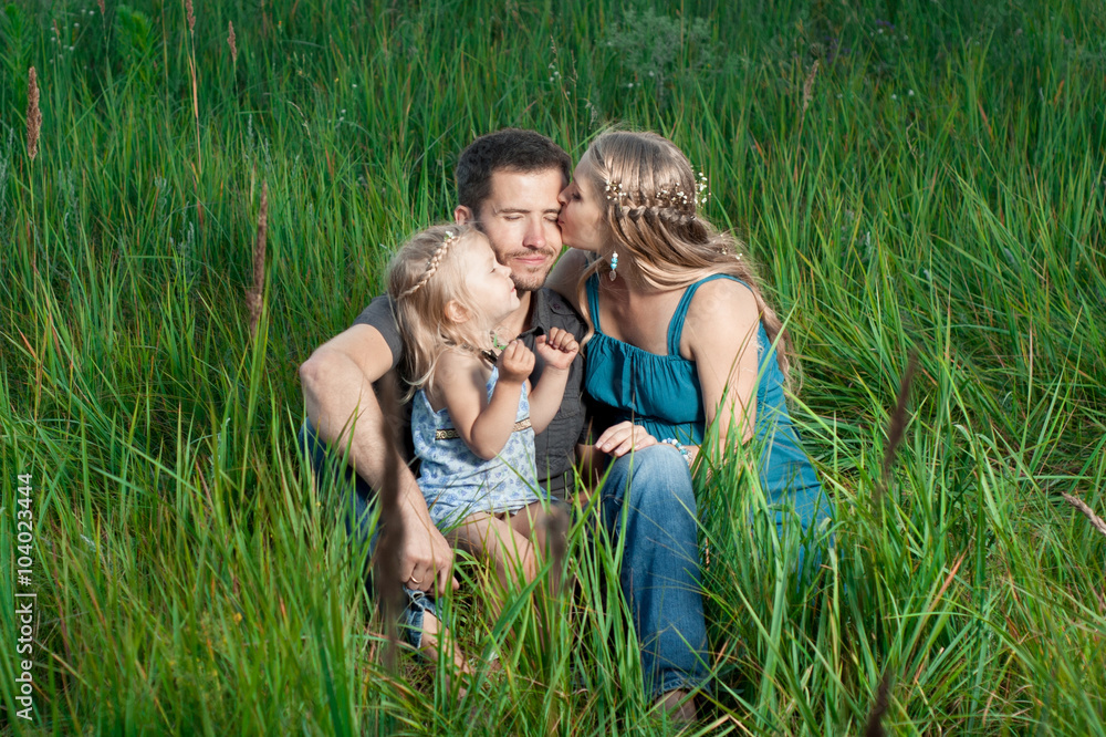 Obraz premium Mother and daughter kissing daddy outdoors. Happy family.