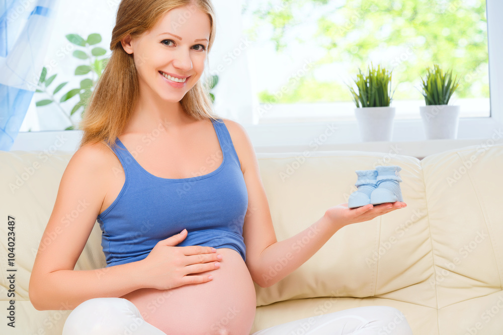happy pregnant woman is resting at home on sofa and holding a bl happy pregnant woman is resting at home on sofa and holding a bl
