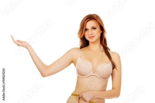 Happy young woman measuring her body and presenting something on open palm