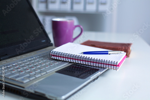 Office table with blank notepad and laptop 