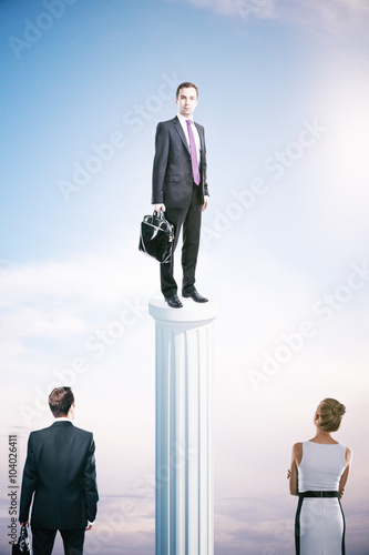 Success concept with businessman on column and other people photo