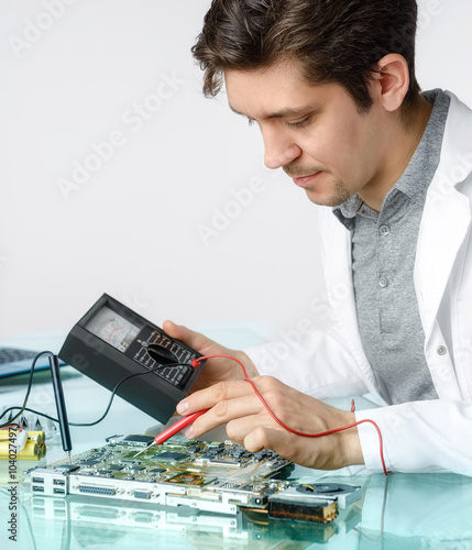 Young energetic male tech or engineer repairs electronic equipme photo