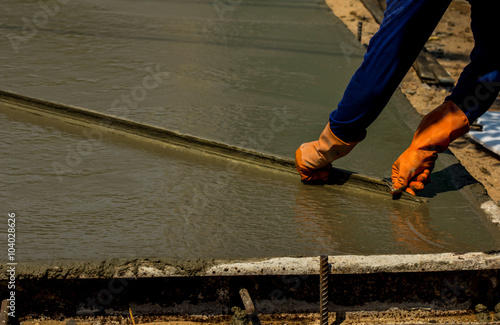 Construction worker spreading wet poured concrete 