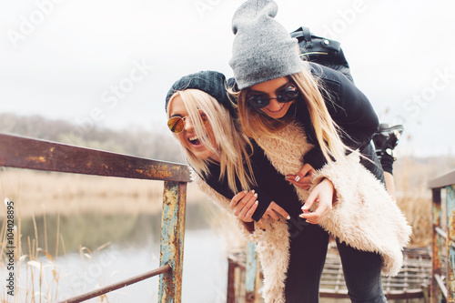 Outdoor lifestyle portrait of two best friends, smiling and having fun together, enjoy each other company posing and making selfie pictures to each other and share happiness
