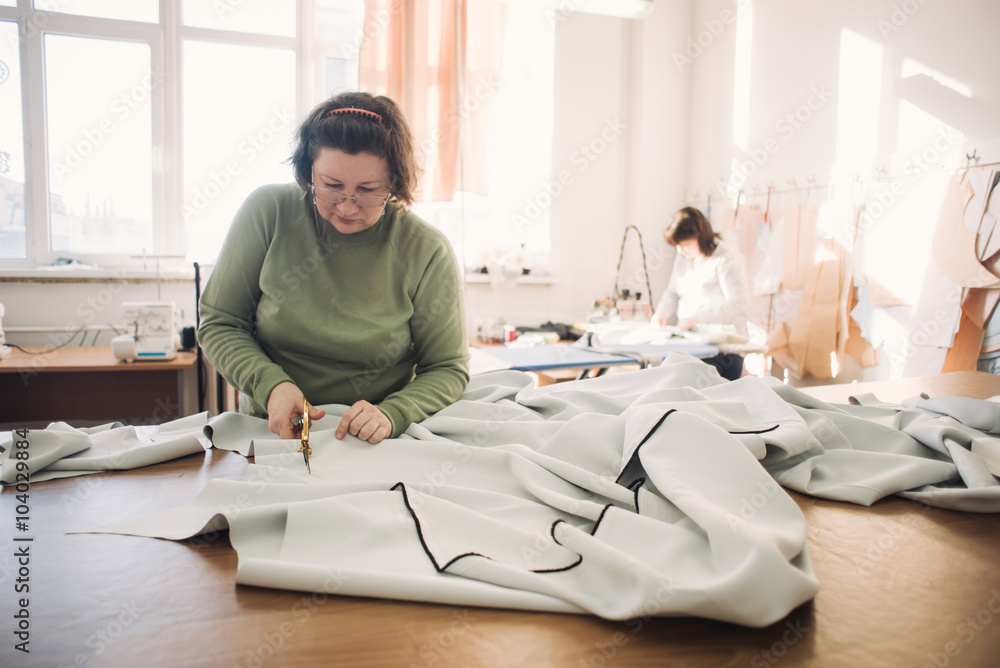 Obraz premium dressmaker working on the shop floor with the fabric scissors