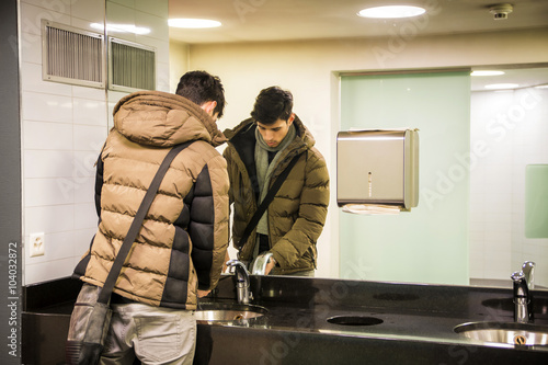 Reflection of man washing hands in bathroom photo