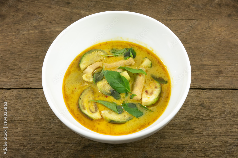 The delicious homemade Thai green curry with pork (Gang Keaw Wan) in white bowl on old wooden planks.