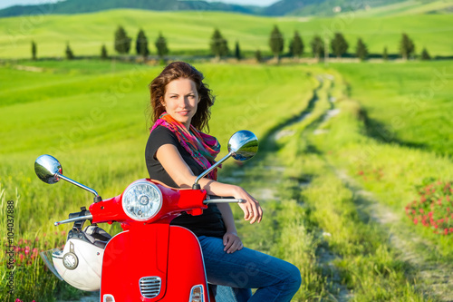 Portrait of toung beautiful woman with a scooter and tuscany landscape in background photo