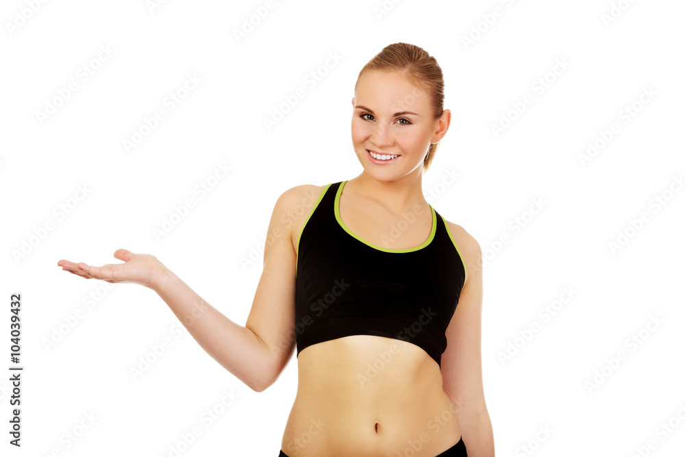 Athletic woman in sports underwear presenting something on open palm Athletic woman in sports underwear presenting something on open palm