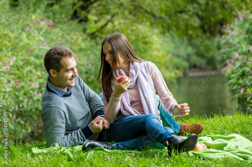 Young beautiful couple having picnic on the lawn in summer park. Woman and man  laughing and having fun. © Suzi Media 