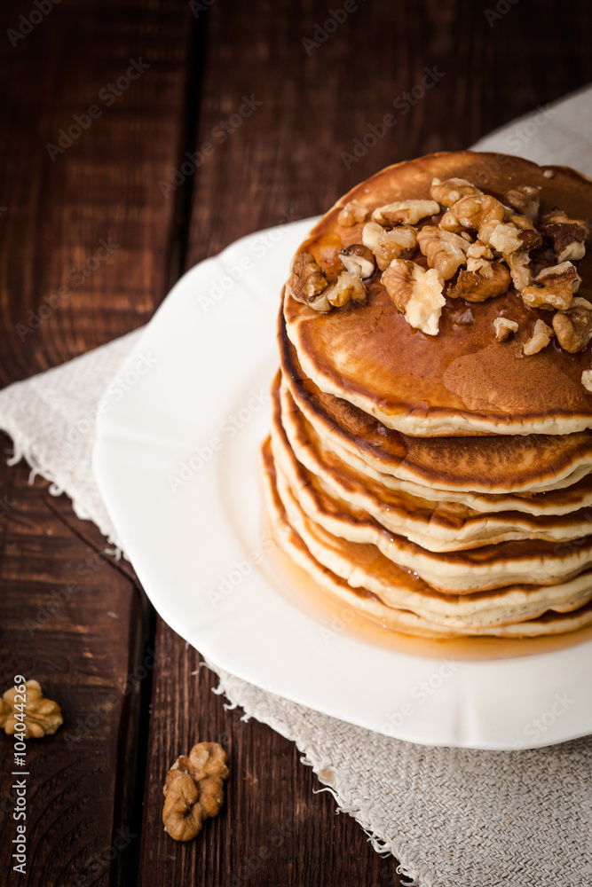 Pancakes with nuts and honey on a dark background