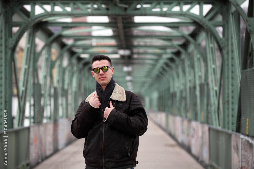 Attractive young man wearing leather jacket and sunglasses on the street Attractive young man wearing leather jacket and sunglasses on the street