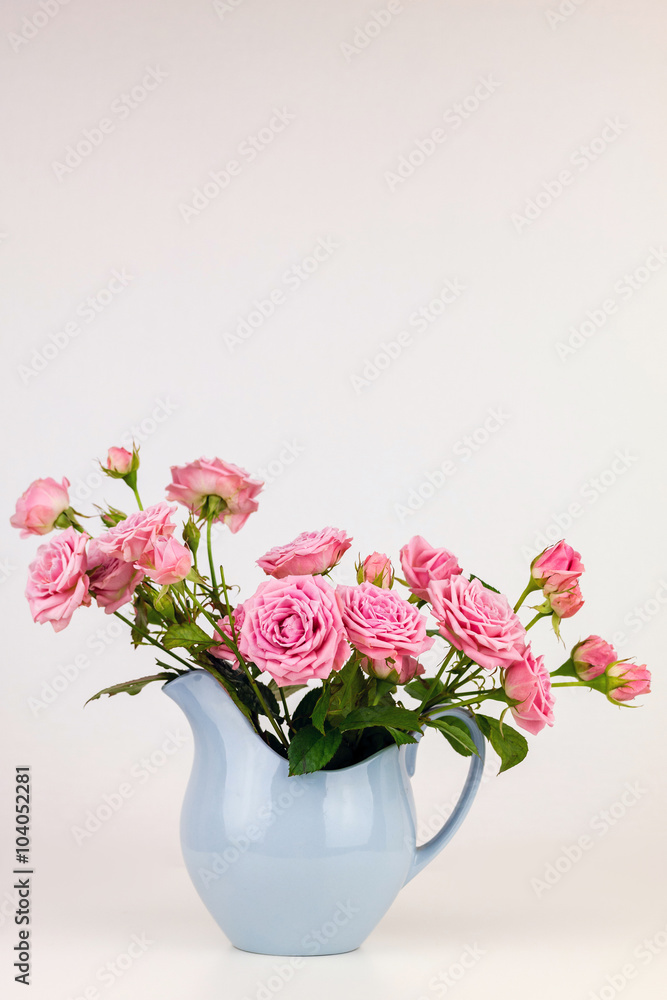 Pink flowers in blue jug. Roses in jug.