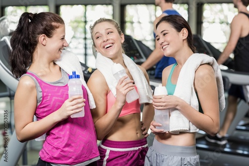 Athletic smiling women posing with bottle of water