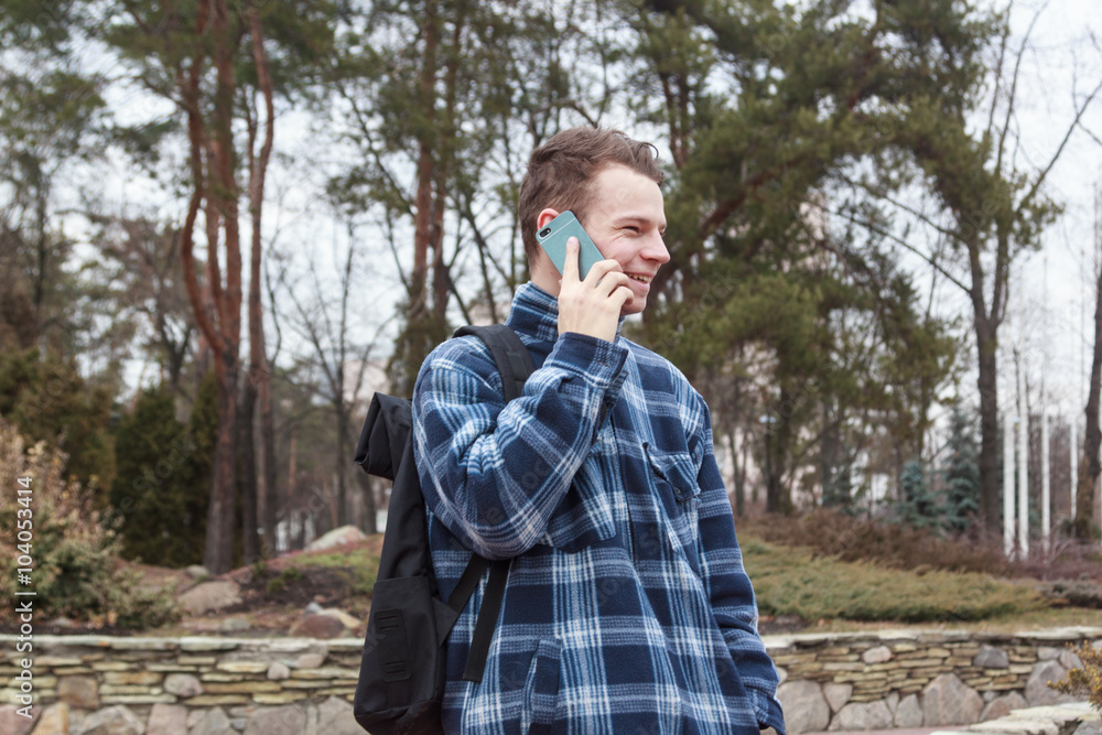 Fototapeta premium guy in town with a backpack talking on the phone