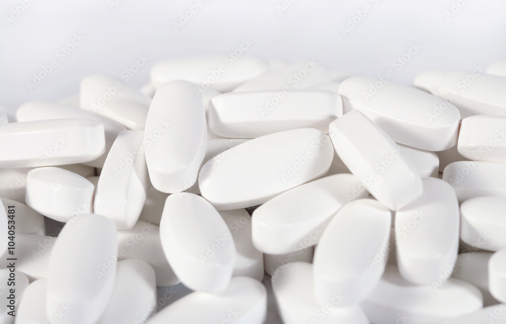 Heap of white pills on a white Heap of white pills on a white