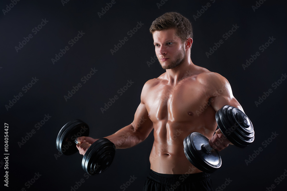 Pulling thorough. Portrait of a handsome young fitness man exercising with dumbbells against black background Pulling thorough. Portrait of a handsome young fitness man exercising with dumbbells against black background