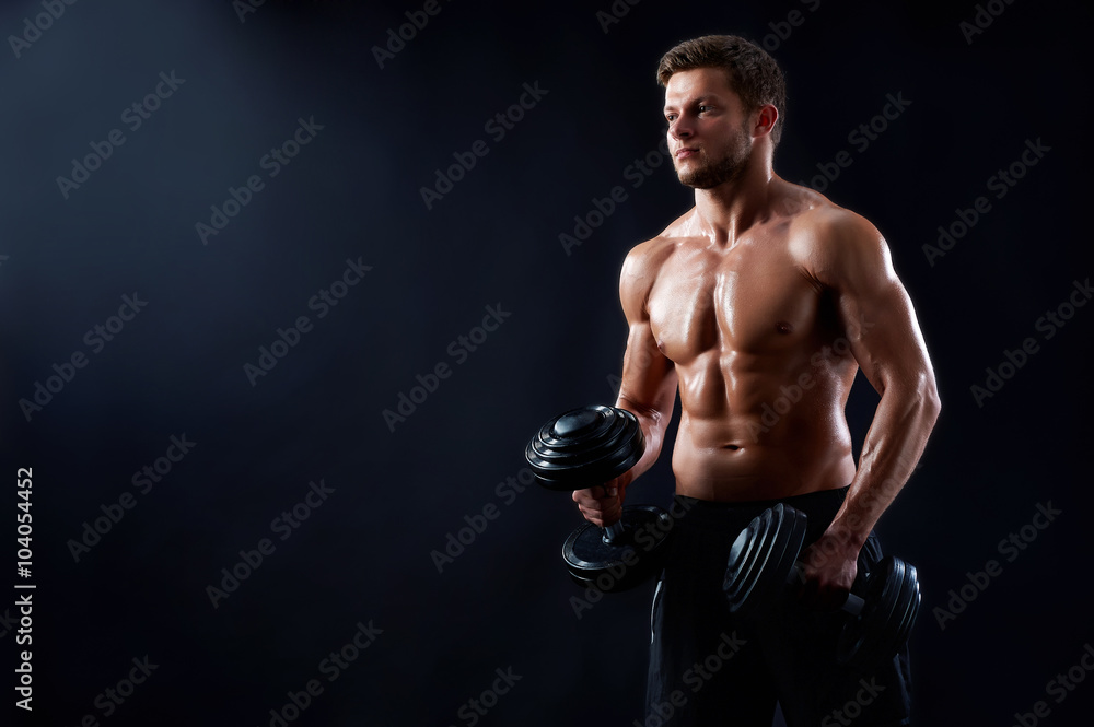 Breathtaking body. Horizontal portrait of a young shirtless fitness man posing with dumbbells showing off his perfect torso copyspace on the side