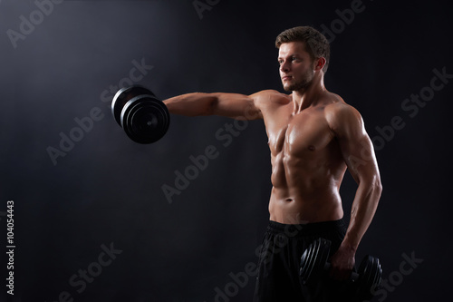 Working on every inch. Studio portrait of a young handsome fit and toned sporty man working out holding dumbbells