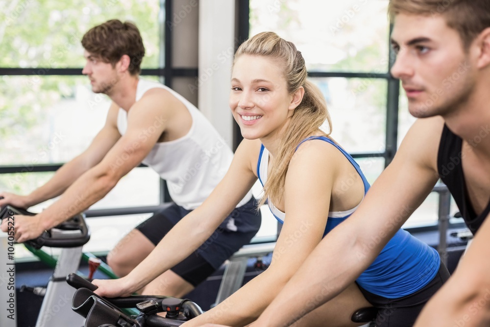 Fit group of people using exercise bike together in gym Fit group of people using exercise bike together in gym