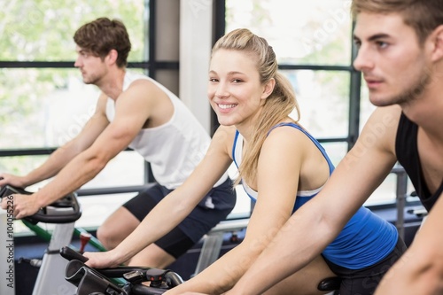 Fit group of people using exercise bike together in gym