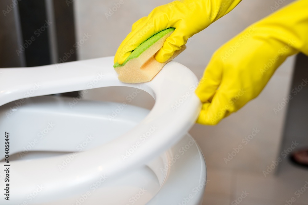  hands cleaning toilet seat in wc with yellow sponge