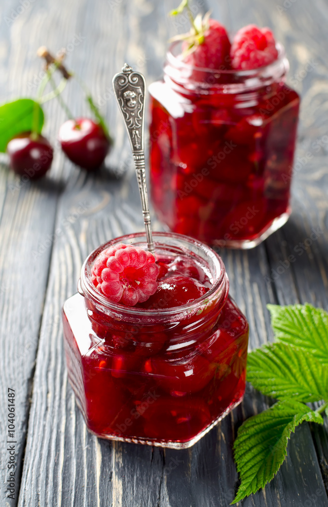 Cherry jam and raspberry on a rustic wooden table Cherry jam and raspberry on a rustic wooden table