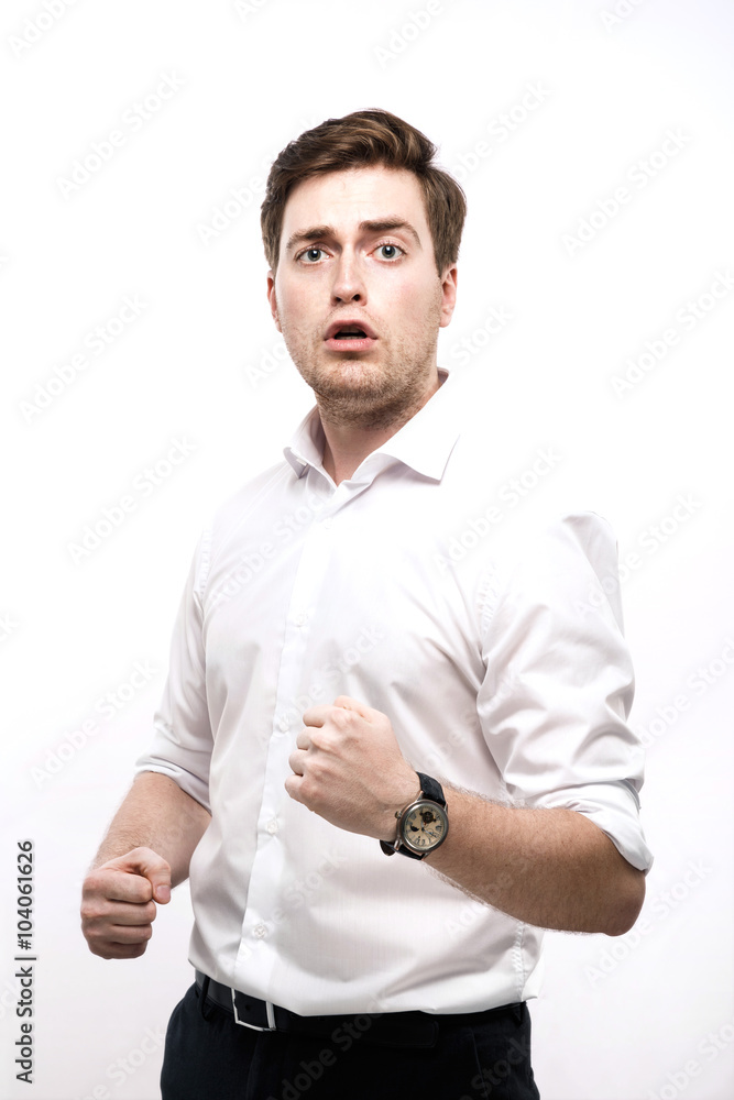 Confused brunette man standing with clenched fists in studio