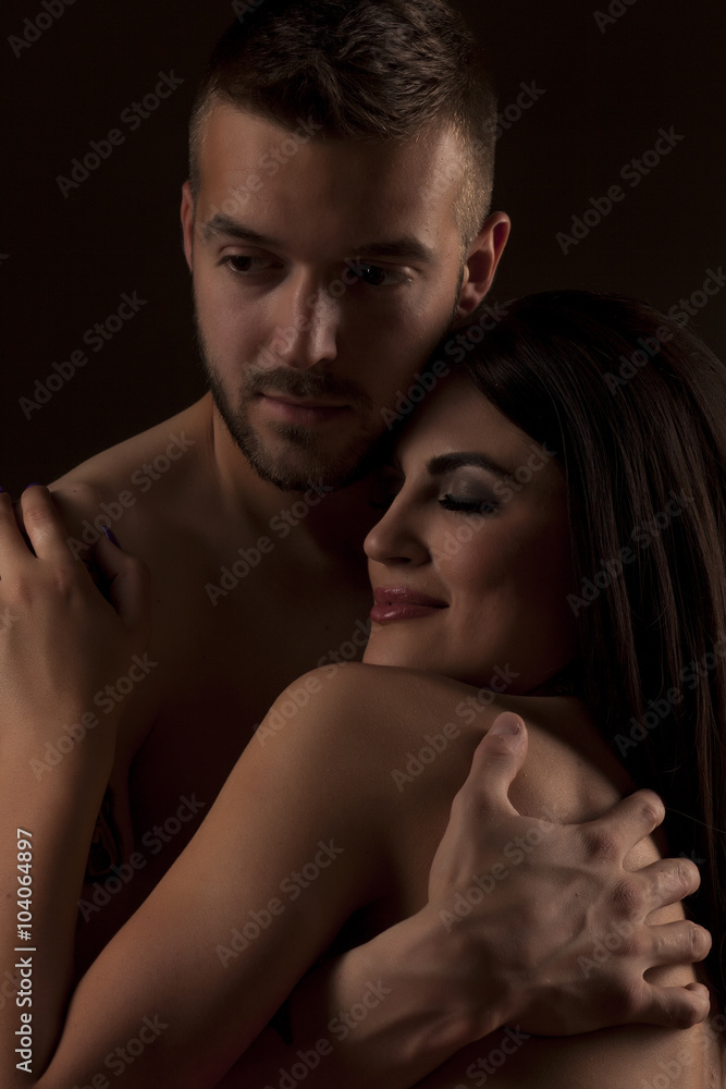 young naked couple in an embrace on black background young naked couple in an embrace on black background
