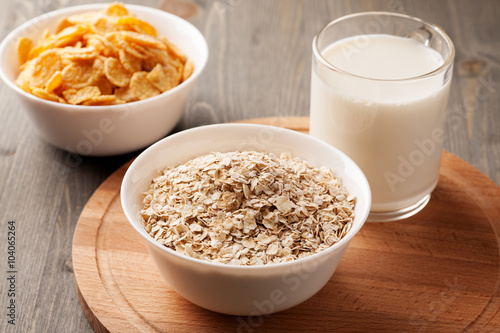 Oatmeal, cornflakes and glass of milk on wooden board