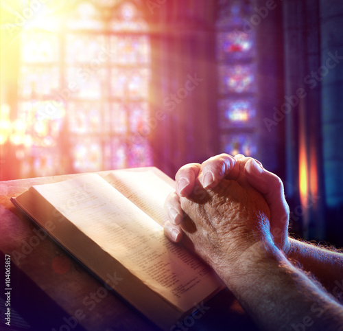 Фотография Hands Of A Man Praying With Bible