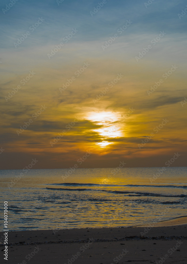 Fototapeta premium Sun sets over horizon of ocean. Sky, water and shore in the even