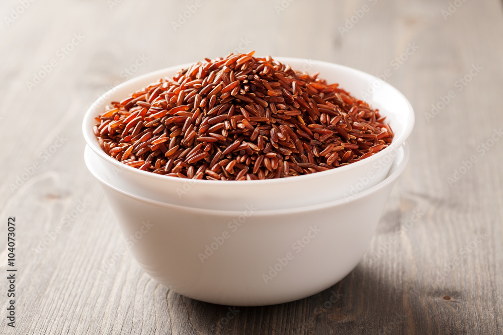 Red rice in two stacked ceramic bowls on wooden table Red rice in two stacked ceramic bowls on wooden table