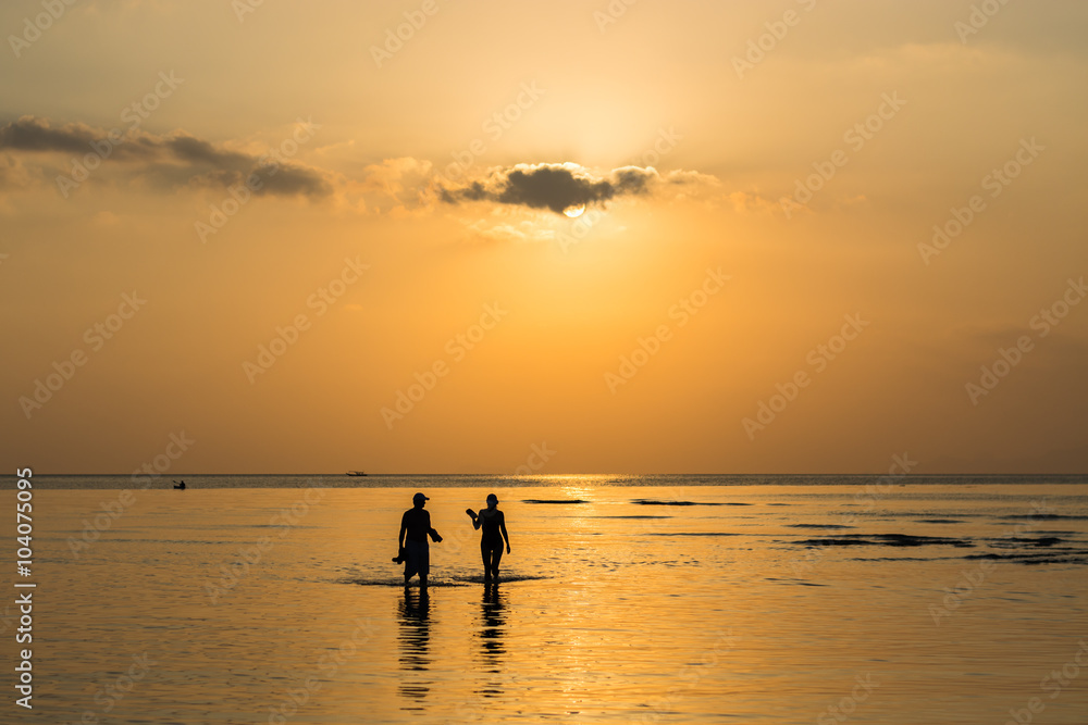 Silhouette couple walking in the sea